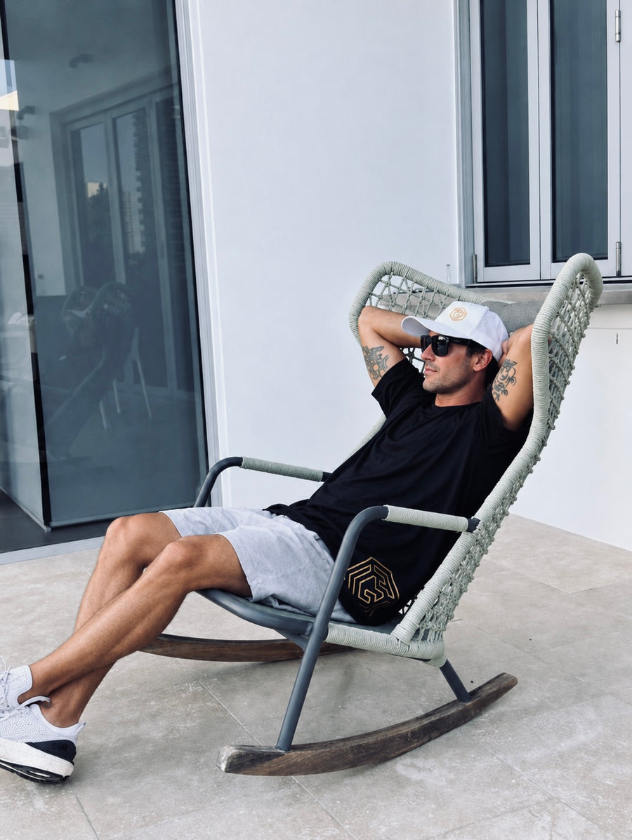Man wearing a black LGLGFG T-shirt and grey shorts relaxing in a deck chair