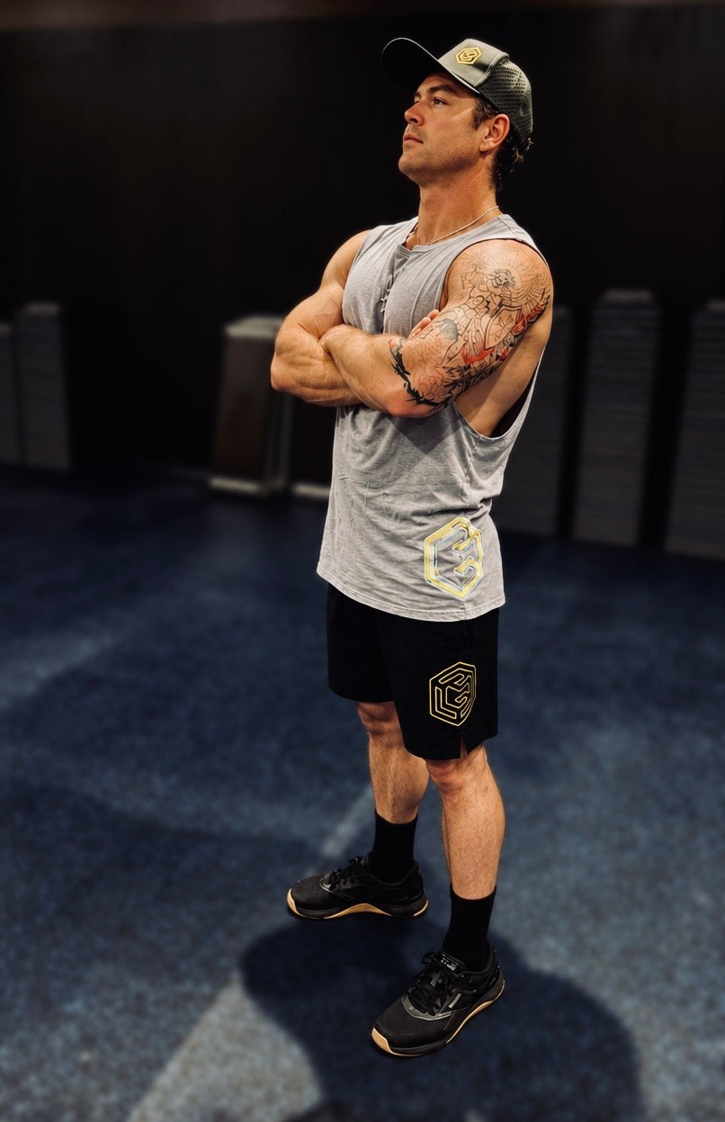 Man wearing a grey LGLGFG tank and black shorts in a gym